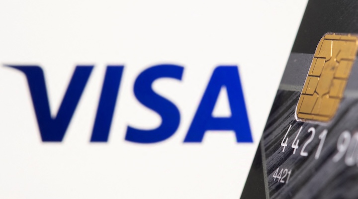 Credit card is seen in front of displayed Visa logo in this illustration.