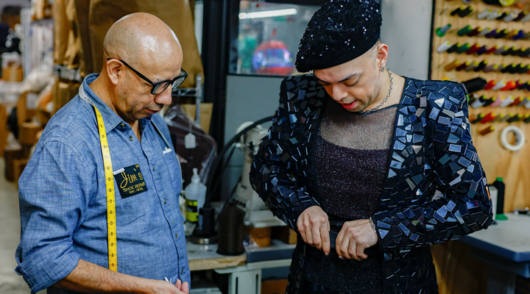A tailor helping a customer try on a belt